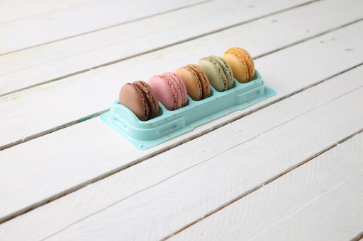 A high angle shot of a set of colorful macaroons on a white wooden surface