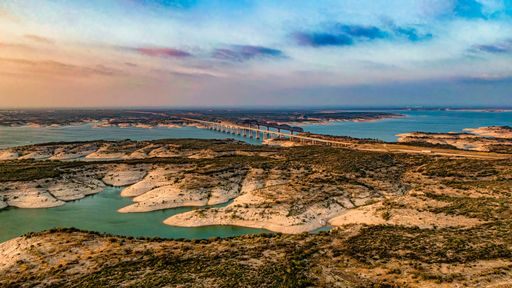 An aerial view of Amistad Reservoir with the Governor's Landing Bridge in Texas at sunset