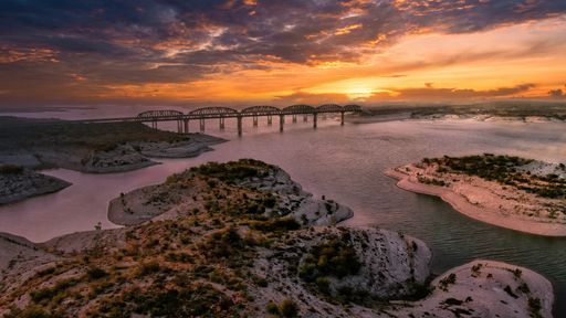 An aerial view of Amistad Reservoir with the Governor's Landing Bridge in Texas at sunset
