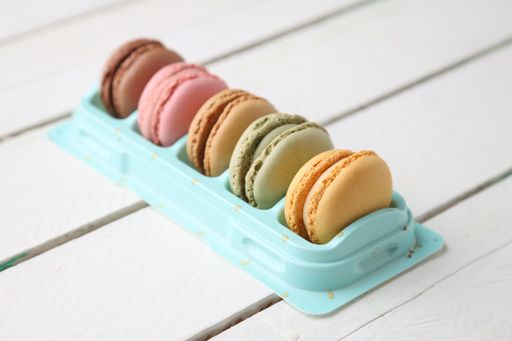 A closeup shot of colorful macarons on a light blue original plate placed on a wooden table
