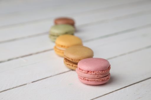 A selective focus shot of different flavors of macarons assorted on a white wooden surface