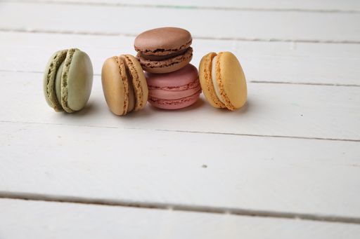 A closeup of tasty and colorful macarons stack on each other and standing on a white table