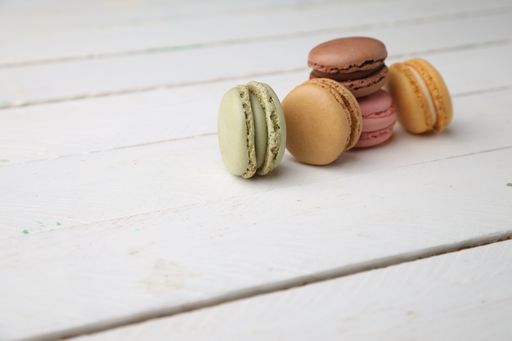 A high angle shot of a set of colorful macaroons on a white wooden surface
