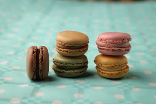 A selective focus shot of different flavors of macarons assorted on a  blue patterned surface