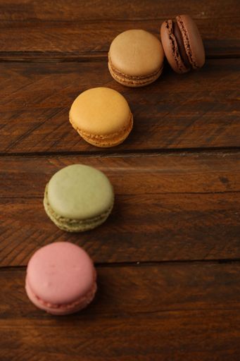 A vertical closeup of tasty and colorful macarons on a brown table