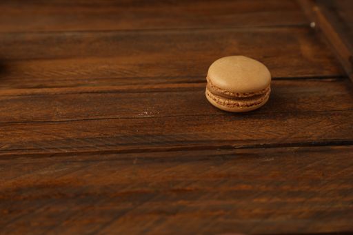 A high angle shot of a chocolate macaroon on a dark brown wooden surface