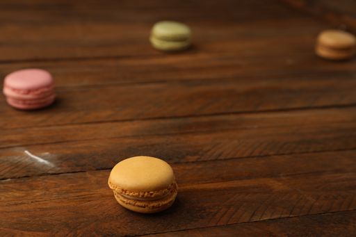A selective focus shot of different flavors of macarons assorted on a wooden surface