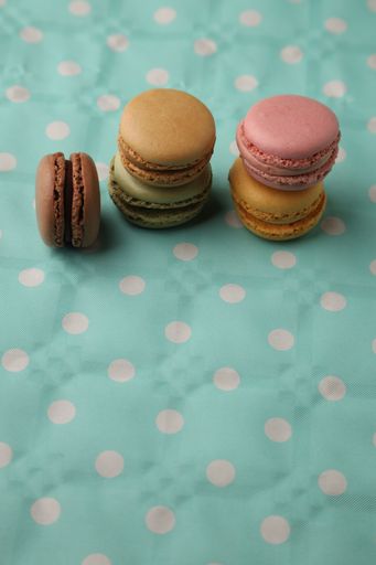 A vertical high angle shot of colorful macarons on a blue spotted surface