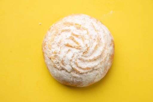 A closeup of a sweet pastry cake decorated with sugar powder isolated on a yellow background