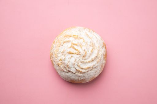 An overhead shot of a powdered pastry on a pink background