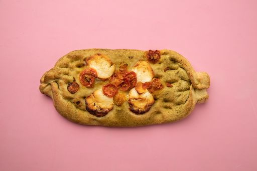 A closeup shot of a non-traditional shaped crispy delicious pizza isolated on a pink background