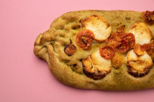 A closeup shot of a non-traditional shaped crispy delicious pizza isolated on a pink background