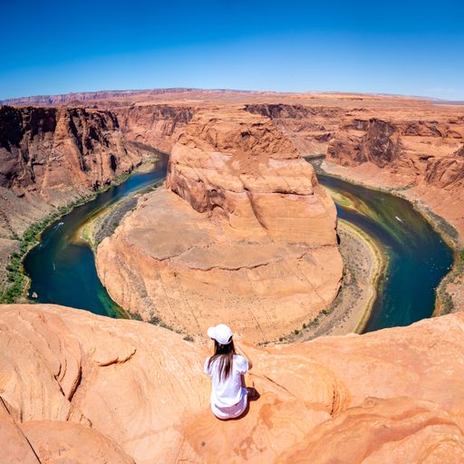 A rear view of a girl with white clothes at Horseshoe Bend in Page on a sunny day