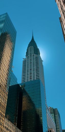 A vertical low angle of the Chrysler Building, one of New York's skyscrapers with a sun behind it