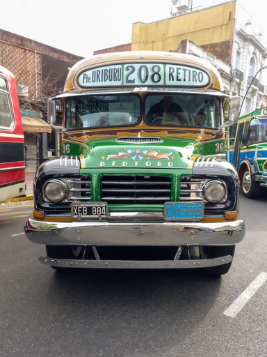 Old green 1960s Bedford bus by GM in street. Public passenger transport in Buenos Aires. Traditional fileteado ornaments. Front view. Classic car show