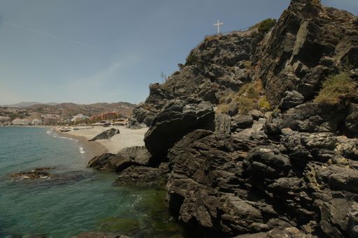 A breathtaking scenery of a seashore with big rocks under the clear blue sky in Spain, Almunecar, cliff San Cristobal