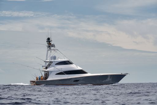 A Viking sportfishing yacht in the ocean under a cloudy pale sky with it passengers fishing