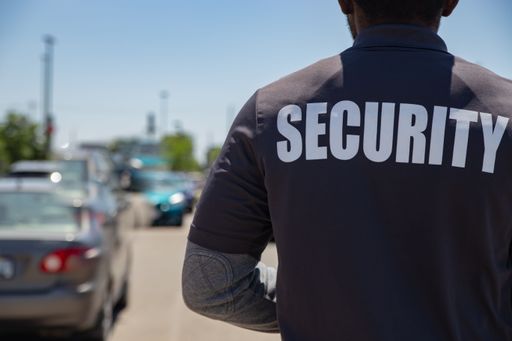 The security person standing at a parking lot, shot from back