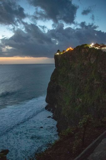 A vertical shot of a high cliff on the seashore during sunset