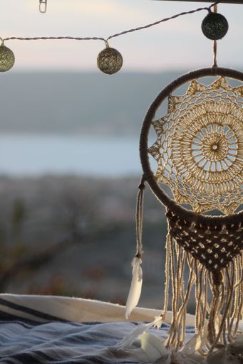 A close-up shot of a dream catcher hanging outdoors with a blurred background