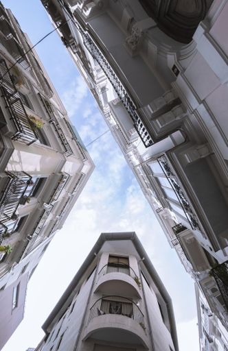 A vertical shot of classic stone buildings with balconies against the blue sky