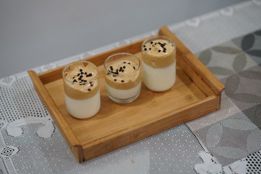 A top view of three glasses of panna cotta on a wooden tray  on a smooth background