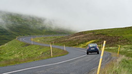 A back view of car on winding asphalt mountain road in Iceland