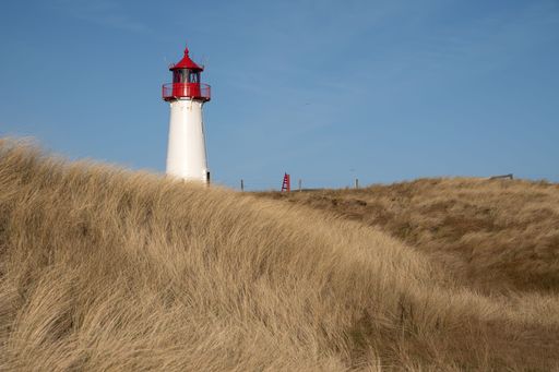 The Leuchtturm List-West lighthouse in yellow field in List auf Sylt, Germany under blue sky