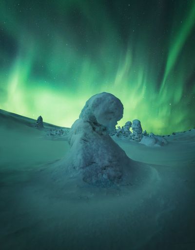 A snow-covered field under the beautiful Aurora Borealis sky