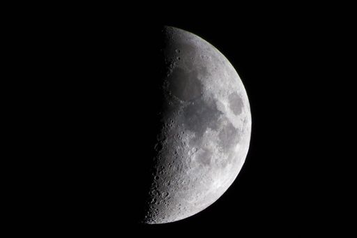 A closeup of a half-moon illuminating the dark night sky