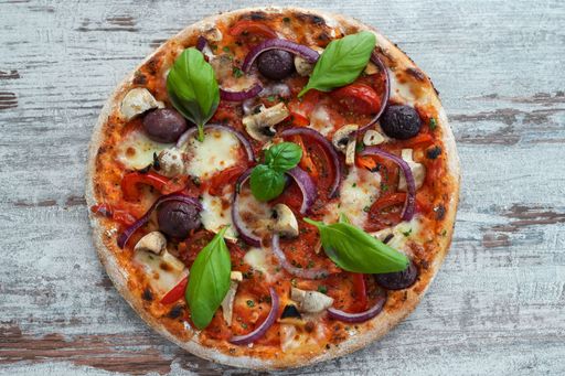 A top view of delicious pizza with mushrooms, basil and onion slices