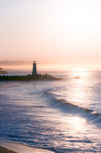 A vertical shot of a lighthouse overlooking a beautiful ocean during the sunset