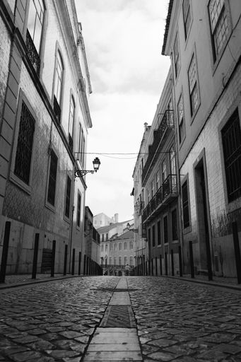 A vertical grayscale shot of an alley between old buildings