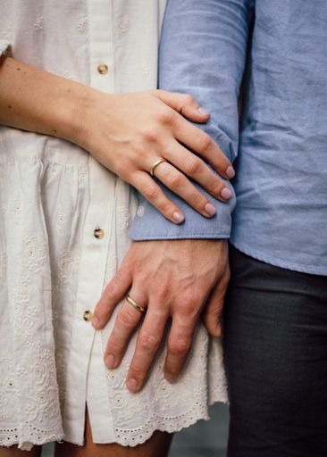 A vertical shot of the hands of a married couple with rings