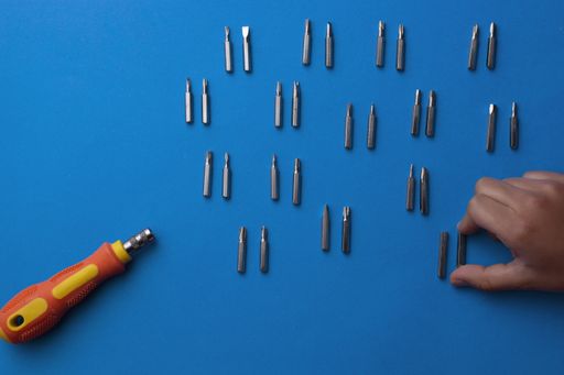 A top view of a screwdriver with many different bits on a blue background