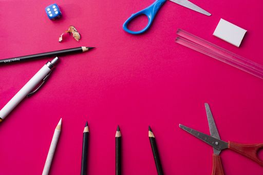 A high angle shot of school supplies on a pink background
