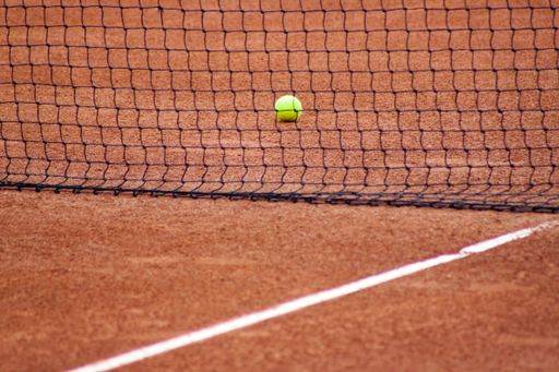 A tennis ball on the field near the net at daytime