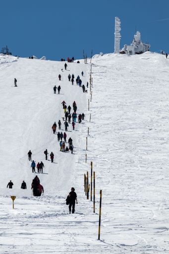 A vertical shot of a group of people climbing the top of a snow-covered mountain