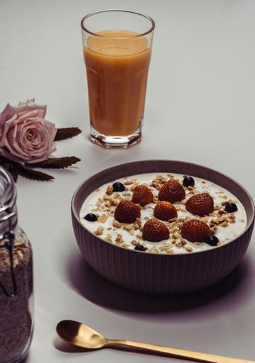 An aesthetic vertical shot of a morning meal with orange juice and a pink rose