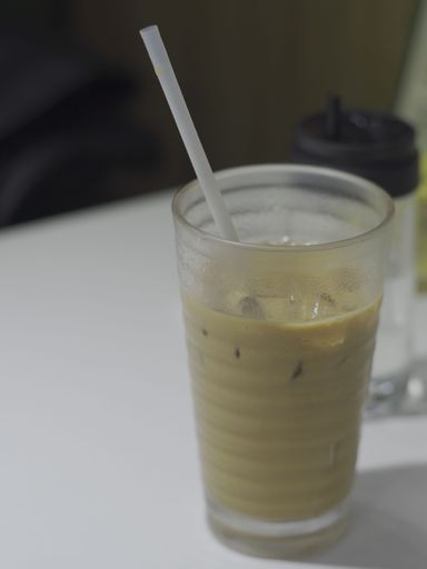 A vertical shot of a glass of ice coffee with a white straw in it