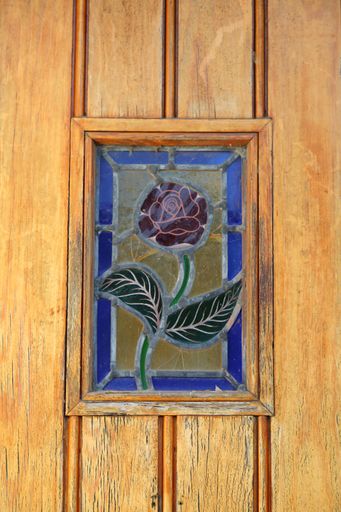 A vertical shot of a stained rose painting hung on a wooden wall