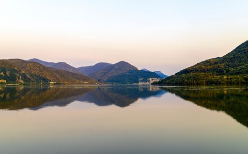 A beautiful view of a reflective calm lake with mountains under the clear sky