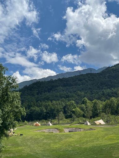A Vertical view of a summer camp with tents and mountains in the background
