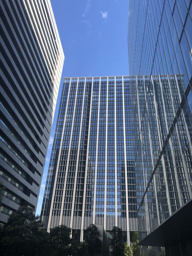 A low angle shot of a glass office building under the clear blue sky in Tokyo, Japan
