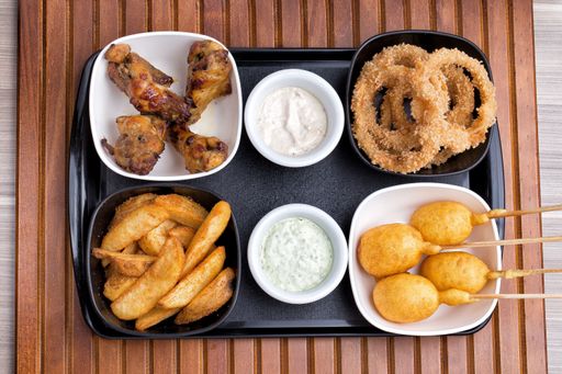 A high angle shot of bowls of chicken, fries, onion rings and grilled cheese