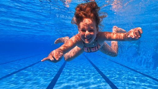An underwater shot of a Caucasian young girl swimming in the pool