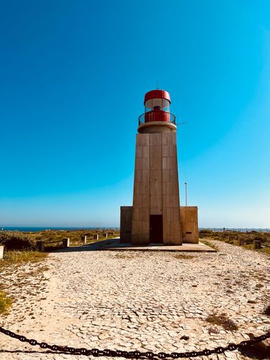 A vertical low angle shot of the Lighthouse of Sagres against a blue sky in Portugal