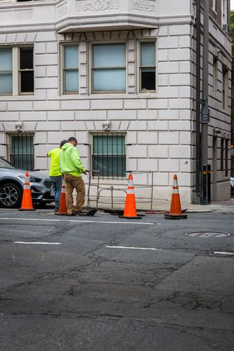 A few construction workers open a utility cover to work under a street in Boston