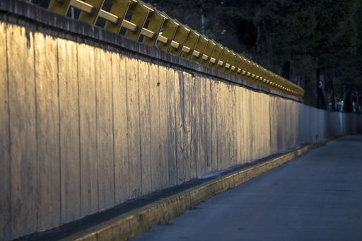 A selective focus shot of a wooden wall leading people to a beautiful evening walk