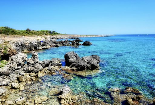A beautiful scenery of a seashore with rocks of different sizes under the clear blue sky